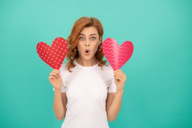 shocked young lady with red heart on blue background.