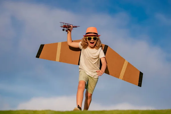 Happy childhood. Child playing with plane wings. Summer kids at countryside. Childhood memories, dream imagination concept. Active child playing outdoor