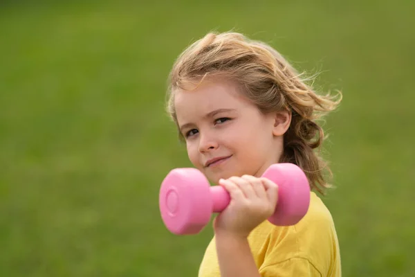 Kids sports exercises. Healthy kids life and sport concept. Portrait of child boy working out with dumbbells. Motivation and sport concept for children