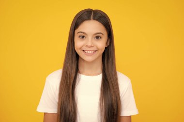 Happy teenager portrait. Portrait of cute positive little girl isolated on yellow background. Attractive caucasian child smiling and looking at camera. Smiling girl