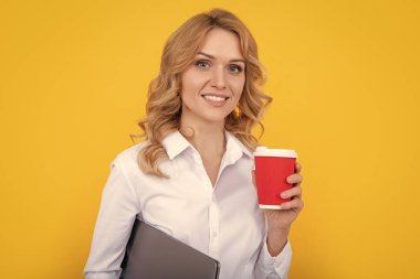Kahve fincanı ve sarı arka planı olan neşeli sarışın kadın..