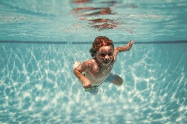 Underwater kids swims in pool, healthy child swimming and having fun under water