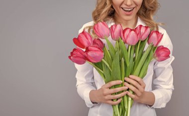 Gri arka planda bahar lale çiçekleri olan sarışın kadın..