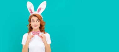 funny easter girl in bunny ears and bow tie on blue background. Woman isolated face portrait, banner with mock up copyspace