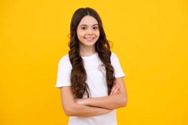 Happy teenager, positive and smiling emotions of teen girl. Portrait of caucasian teen girl with arms folded, isolated on yellow background. Cute teenager child