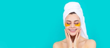 Skin care beauty woman. glad young girl has collagen gold eye patches on face with towel. Beautiful woman isolated face portrait, banner with mock up copy space
