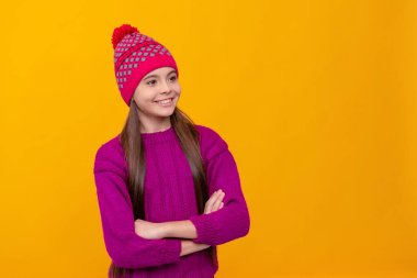 happy child in knitted hat. kid wear warm clothes on yellow background. children winter fashion and beauty. teen girl in knitwear. express positive emotion. copy space.