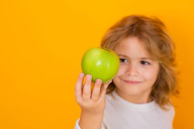 Stüdyoda elmalı çocuk. Stüdyo portresi sarı arka planda elma tutan şirin bir çocuk.