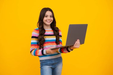 School student using laptop. E-learning and online education. Teen girl on internet video chat isolated on isoalted yellow background. Happy teenager, positive and smiling emotions of teen schoolgirl