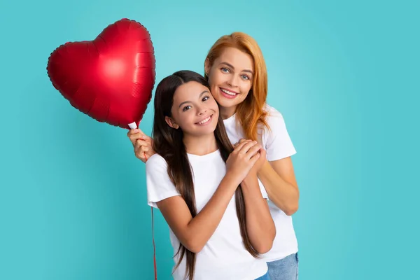 Valentines day. Smiling mother and daughter holding love heart balloon on blue background. Happy Valentines day to my mom