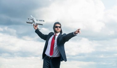 businessperson in suit and pilot hat launch plane toy on sky background.