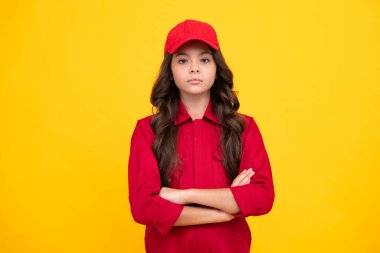 İşçi çocuk tulumlu ve kırmızı şapkalı. Sarı arka planda kapalı stüdyo çekimleri