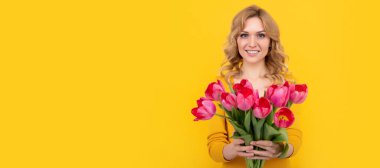 happy young beautiful woman with spring tulip flowers on yellow background. Woman isolated face portrait, banner with mock up copy space