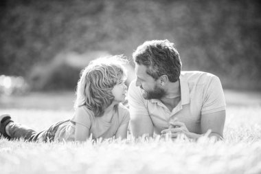 Çocukluk ve ebeveynlik. Ebeveyn, küçük çocuk çimlerin üstündeyken rahatlar. Baba ve çocuk yaz günü. Ebeveynlik ve babalık. Babalar günü. Baba ve oğlunun parkta eğlenmesine sevindim. aile değeri.