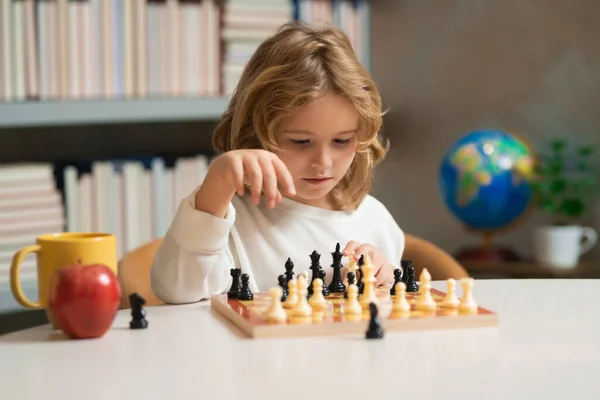 Clever concentrated and thinking child playing chess. Logic game for kids and logical thinking