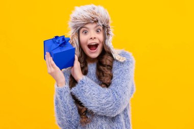 winter shopping sale. birthday present box. christmas season. amazed curious kid with purchase in hat. boxing day. teen girl in knitwear on yellow background. child buy gift. black friday discount.
