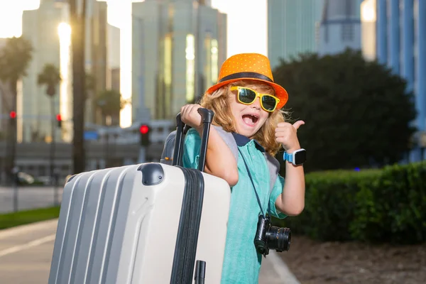 Child traveler with suitcase outdoor. Tourist kid boy having cheerful holiday trip. Child travel with travel bag. Child with suitcase dreams of travel, adventure, vacation
