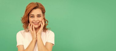 Woman isolated face portrait, banner with copy space. smiling girl with curly hair touch her perfect skin on blue background, copy space, skin and hair
