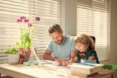homeschooling and self-education. back to school. busy father and son painting at home. family help. boy do homework with teacher. private writing lesson. education concept.