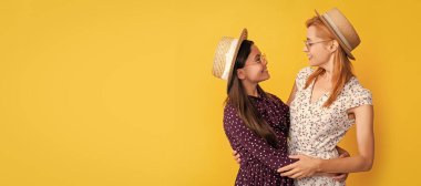 Anne ve kız çocuk afişi, kopyalama alanı, izole bir arka plan. Sarı arka planda hasır şapkalı gülümseyen anne ve kız.