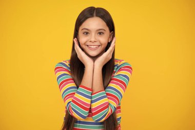 Happy face, positive and smiling emotions of teenager girl. Emotional portrait of caucasian teenager child girl isolated on studio yellow background