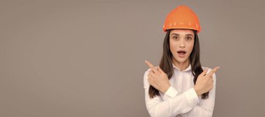 Woman isolated face portrait, banner with mock up copy space. Architect woman wearing helmet over gray background, pointing finger