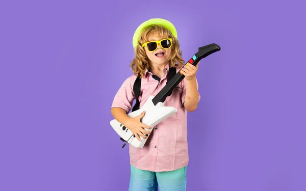 Cute boy plays on the electric guitar with funny glasses. Funny little hipster musician child playing guitar