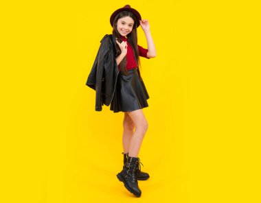 Full length photo of pretty teenager child girl wear casual clothes leather skirt isolated on yellow background. Happy teenager portrait. Smiling girl