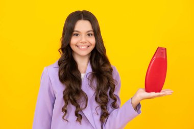 Teenage girl with shampoos conditioners or shower gel. Kids hair care cosmetic product, shampoo bottle. Happy teenager, positive and smiling emotions of teen girl