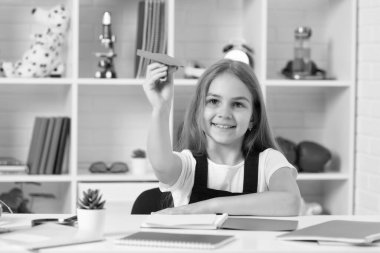 gülümseyen çocuk okul sınıfında kağıt uçakla oynuyor..