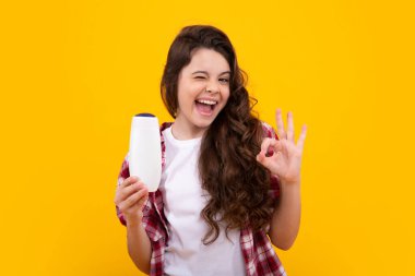 Şaşırmış bir genç. Genç kız şişe şampuanı ya da duş jeli gösteriyor. Saç kozmetik ürünü. Reklam için şişe fotokopi alanı oluşturun. Heyecanlı genç kız