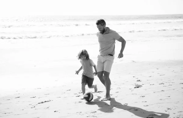 happy father and son playing football having fun on summer sandy beach family vacation, football.