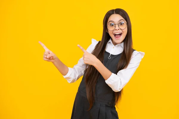 Excited face, cheerful emotions of teenager girl. Close-up portrait of her she nice cute attractive cheerful amazed girl pointing aside on copy space isolated on yellow background