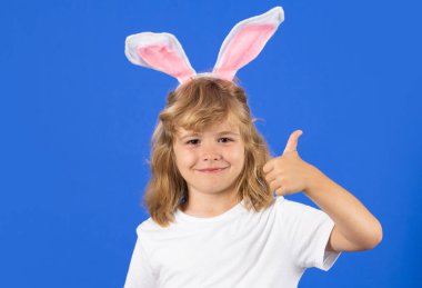 Portrait of cute child with bunny ears with thumbs up, isolated on studio background