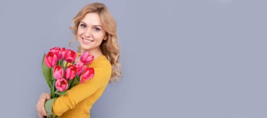 glad girl hold flowers for spring holiday on grey background. Woman isolated face portrait, banner with mock up copy space