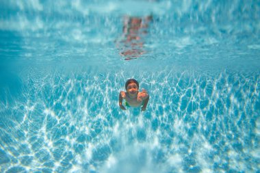 Çocuk yüzüyor ve suyun altına dalıyor. Yüzme havuzundaki su altı portresi. Çocuk yüzme havuzuna dalıyor.