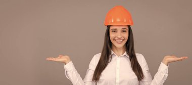 İzole edilmiş bir yüz portresi, taklit alanı olan bir afiş. Koruyucu kasklı ve beyaz gömlekli mutlu kadın ürün, fotokopi alanı, reklam sunar.