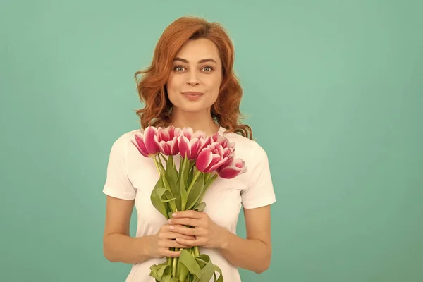 positive woman with tulip flower bouquet on blue background.