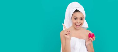 amazed kid in bath tower applying skin cream, cosmetic. Cosmetics and skin care for teenager child, poster design. Beauty kid girl banner with copy space