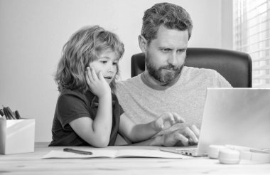 Olgun erkek öğretmen ya da baba çocuğuna bilgisayar ödevinde yardım ediyor..