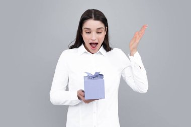 Gri arka planda hediye kutusunu tutan güzel bir kadın.