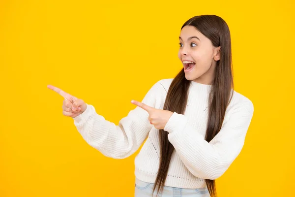 Teenager child pointing to the side with a finger to present a product or idea. Teen girl in casual outfit pointing empty space. Excited face. Amazed expression, cheerful and glad