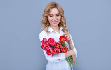 glad young woman with spring tulip flowers on grey background.