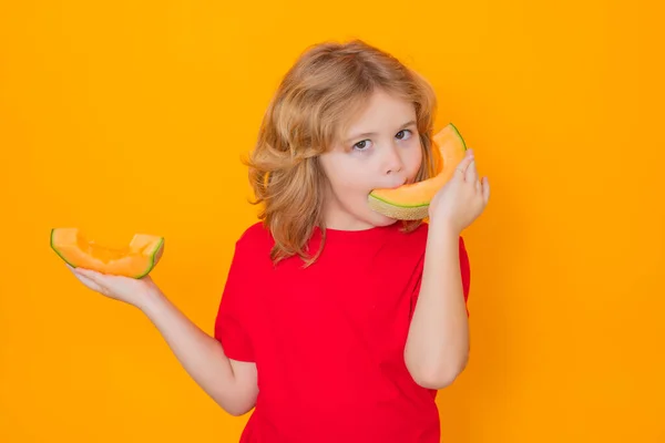 Kids face with fruits. Child eat red melon in studio. Melon fruit. Studio portrait of cute kid boy with melon isolated on yellow