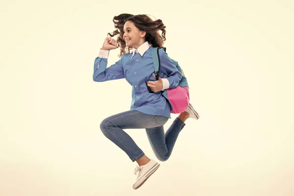 Schoolgirl in school uniform with school bag. Run and jump. Schoolchild, teen student hold backpack on white isolated background