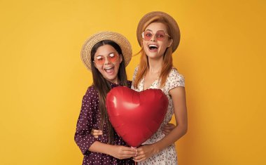 Sarı arka planda aşk balonu tutan anne ve kız hayrete düştü..