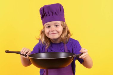 Çocuk tencereyle yemek pişiriyor. Aşçı üniformalı küçük bir çocuğun portresi. Şef çocuk stüdyo arka planında izole edilmiş. Aşçı olmak için sevimli bir çocuk. Aşçı şapkası giymiş bir çocuk.