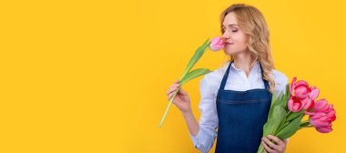 Sarı arka planda bahar lale çiçekleri olan önlüklü mutlu bir kız. İzole edilmiş yüz portresi, taklit alanı olan pankart