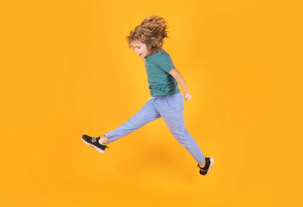 Child boy jump fly movement wear shirt and jeans isolated on yellow studio background