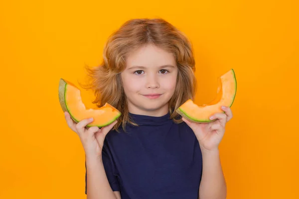 Melon. Child hold red melon in studio. Melon fruit. Studio portrait of cute kid boy with melon isolated on yellow